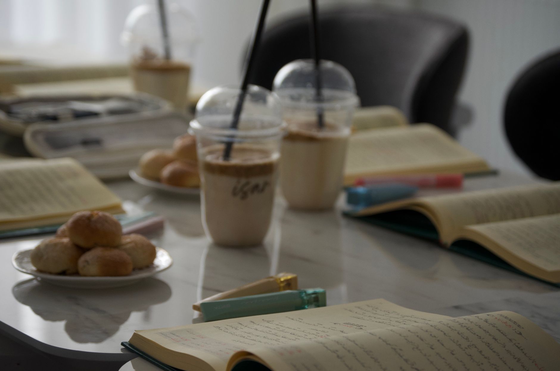 Notebooks and coffee arranged around a shared table